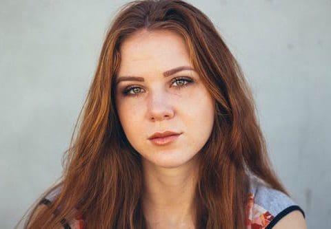 Young woman with auburn hair looking directly at camera