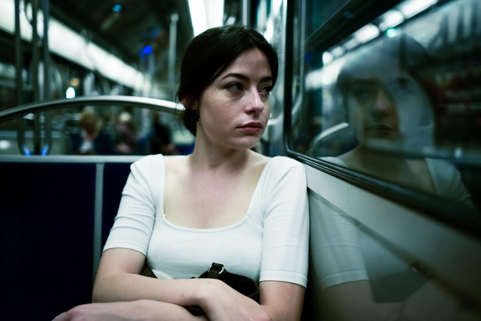Woman on bus or train looking out of window solemnly