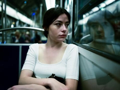 Woman on bus or train looking out of window solemnly