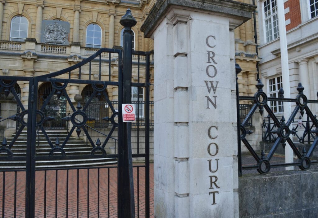 gate and concrete pillar outside a big building. The concrete pillar has writing which says CROWN COURT
