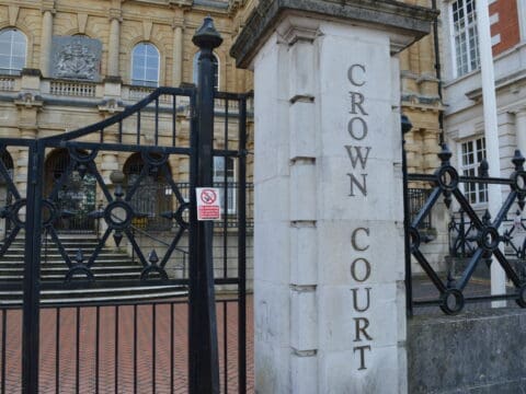 gate and concrete pillar outside a big building. The concrete pillar has writing which says CROWN COURT