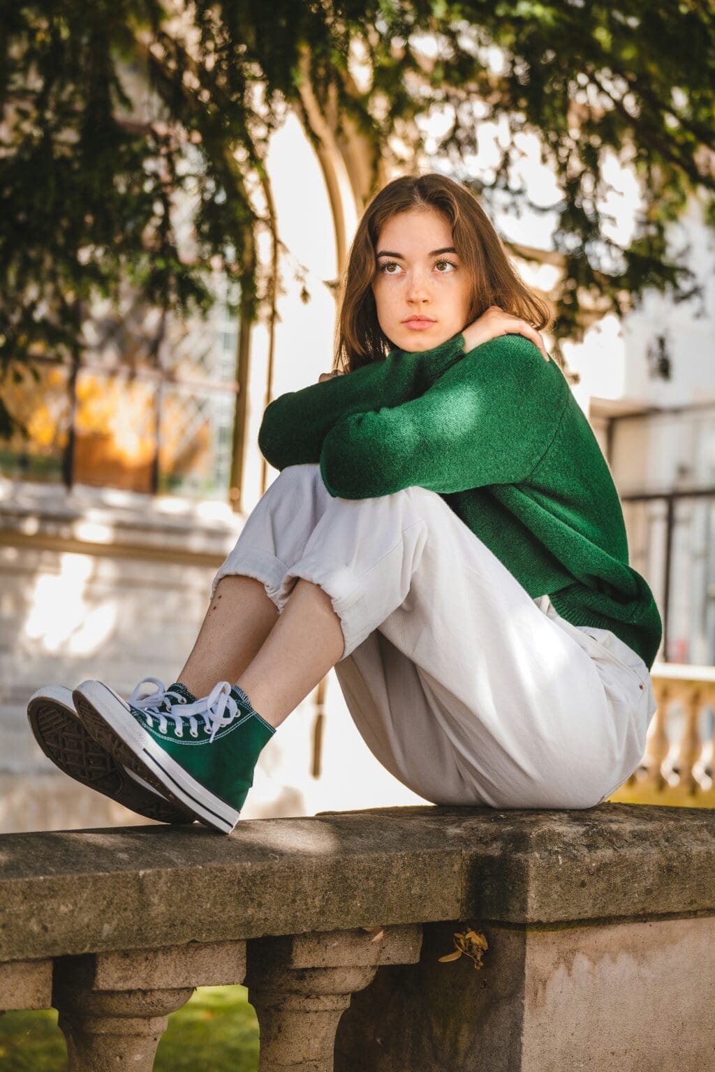 teenage girl with brown hair. She is sitting outside looking out into the distance.